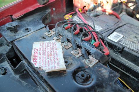 1990 Ford Bronco - Close-up of an engine bay showing two batteries and a complex network of red and black electrical wiring.