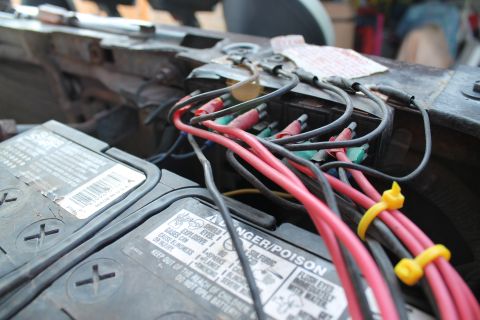 1990 Ford Bronco - Close-up view of a vehicle's engine bay, showing two batteries and a complex wiring harness.