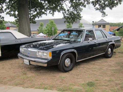 1991 Ford LTD Crown Victoria - dark blue Ford LTD Crown Victoria full-size sedan sits on grass at an outdoor car show with a stop sign and pavilion behind.