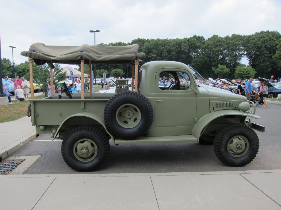 Olive-green vintage Dodge military pickup with canvas-rack bed parked at a show