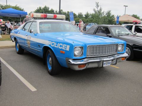 1991 Ford LTD Crown Victoria - Front three-quarter view of a light blue Plymouth police sedan with chrome grille and roof light bar at an outdoor show.
