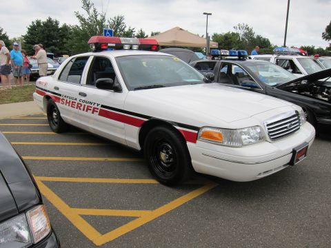 1991 Ford LTD Crown Victoria - white Ford Crown Victoria lettered Cayuga County Sheriff with a red stripe and roof light bar parks in a marked lot.