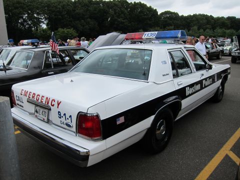 1991 Ford LTD Crown Victoria - Rear three-quarter view of a black-and-white Ford Boston Police sedan marked Emergency Call 911 with roof light bar.