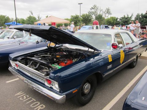 1991 Ford LTD Crown Victoria - dark blue full-size police sedan with hood raised, gold door shield and roof light sits over a VISITOR space at a show.