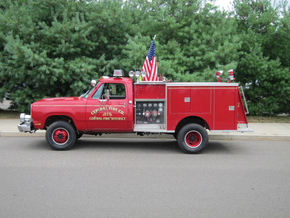 Red Central Fire Co. Dodge 4x4 pumper truck with U.S. flag at the curb