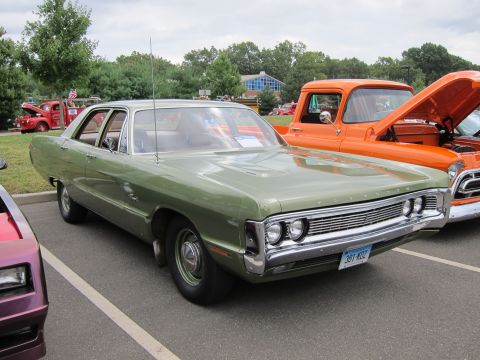 1991 Ford LTD Crown Victoria - green vintage full-size four-door sedan parked on grass at a car show, with an orange pickup and other classics nearby.