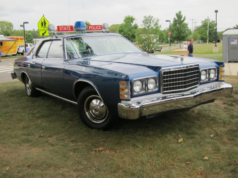 1991 Ford LTD Crown Victoria - blue vintage Ford state police sedan with roof light bar parked on grass, front three-quarter view, at a car show.
