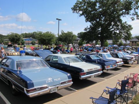 1991 Ford LTD Crown Victoria - row of vintage State Police and Highway Patrol sedans parked at a car show with lawn chairs in the foreground.