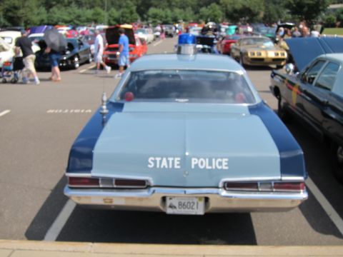 1991 Ford LTD Crown Victoria - Rear view of a light-blue and dark-blue State Police sedan with a roof beacon, license plate 86021, at a crowded car show.