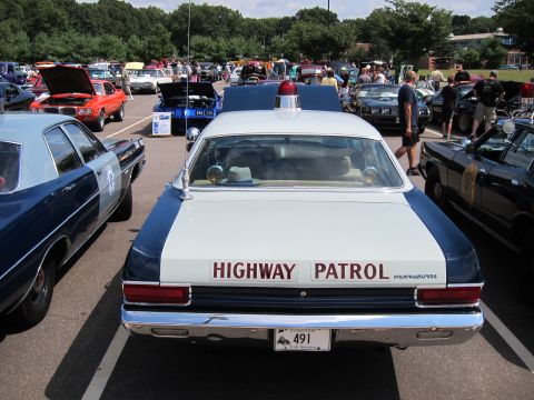 1991 Ford LTD Crown Victoria - Rear view of a blue-and-white Highway Patrol sedan with roof beacon and plate 491, parked among other show cars.
