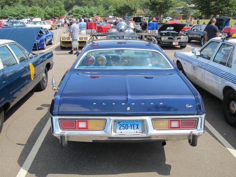 1991 Ford LTD Crown Victoria - Rear view of a blue Plymouth sedan with chrome bumper and plate 250-YEX, parked among police and show cars.