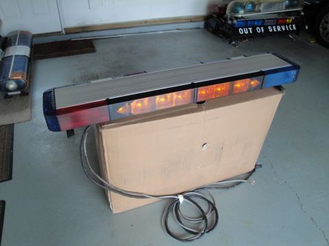 1991 Ford LTD Crown Victoria - An emergency light bar with multiple amber lights is displayed on a cardboard box, with another light bar visible in the background.