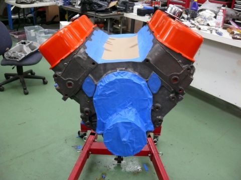 1968 Chevrolet Camaro - An engine block, masked with blue and tan tape, sits on a red engine stand in a workshop.