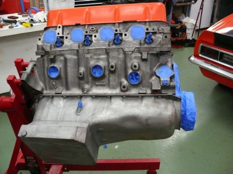 1968 Chevrolet Camaro - Engine block on stand, with a red 1968 Chevrolet Camaro visible in the background.