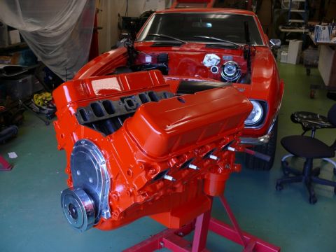 1968 Chevrolet Camaro - A freshly painted V8 engine is displayed in front of a red car in a garage.