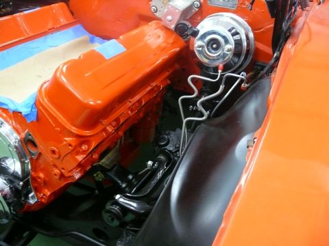 1968 Chevrolet Camaro - The engine bay of a 1968 Chevrolet Camaro features bright orange valve covers and a visible brake booster assembly.