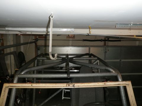 1961 International Scout 800 - A custom roll cage is being worked on inside a garage, with a hook suspended from the ceiling.