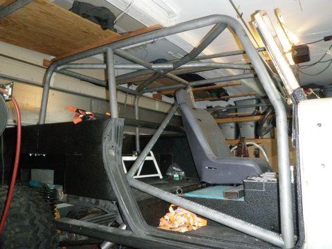 1961 International Scout 800 - The interior of a vehicle is shown with a custom-built roll cage and a driver's seat installed.