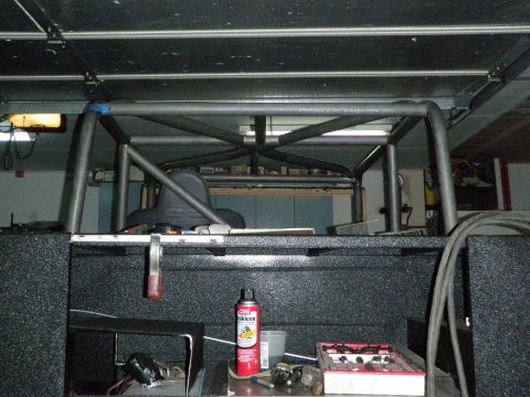 1961 International Scout 800 - Custom roll cage structure visible inside a truck bed, with various tools and supplies nearby.