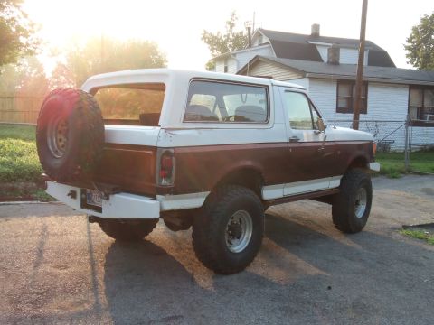 1989 Ford Bronco - A two-tone brown and white Ford Bronco is parked in a driveway with a house in the background.