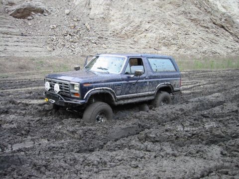 1985 Ford Bronco - This Ford Bronco is deeply stuck in thick mud, with only the top half visible.