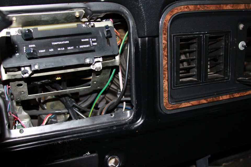 Dashboard with HVAC control panel removed exposing wiring and heater vents