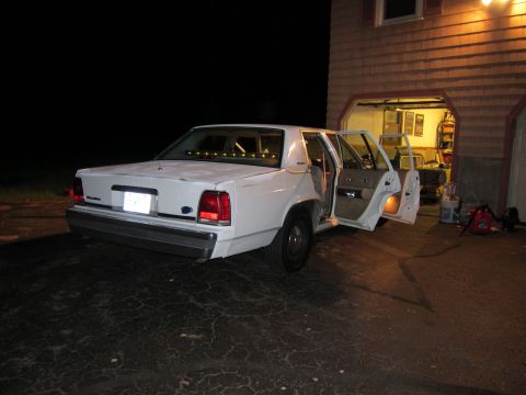 1991 Ford LTD Crown Victoria - Rear view of a 1991 Ford Crown Victoria LTD parked outside a garage at night.