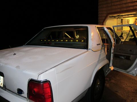 1991 Ford LTD Crown Victoria - The rear of a white sedan is shown with its doors open, parked in a driveway at night.