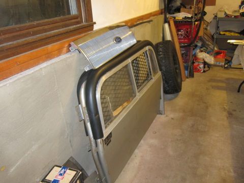 1991 Ford LTD Crown Victoria - A Ford truck bed cap and a spare tire are stored indoors next to a window.