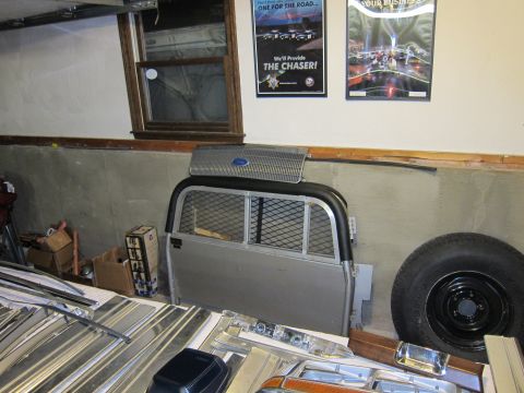 1991 Ford LTD Crown Victoria - A Ford grille and truck cap are stored in a garage with other vehicle parts.