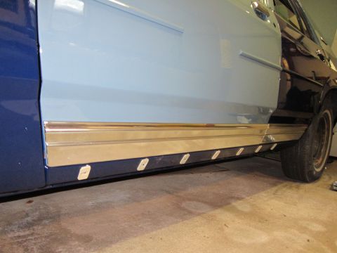 1991 Ford LTD Crown Victoria - The side of a car shows two-tone paint and chrome trim along the rocker panel, with white clips visible.