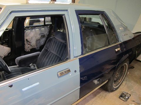 1991 Ford LTD Crown Victoria - A two-tone sedan with its interior partially disassembled, showing velour seats and removed door panels.
