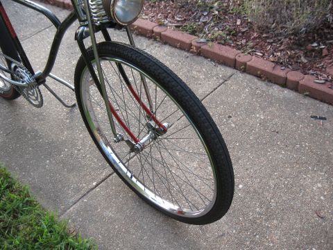 1994 Ford Bronco - The front wheel of a bicycle is shown parked on a sidewalk next to a garden bed.