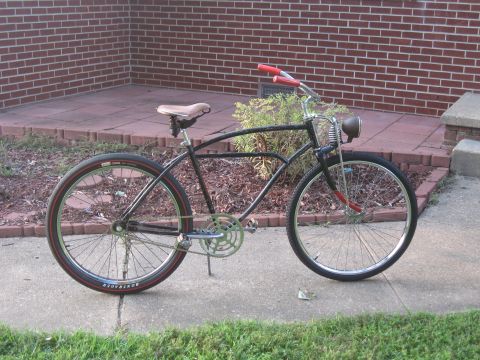 1994 Ford Bronco - A black cruiser bicycle with red handlebars and a tan seat is parked on a sidewalk.
