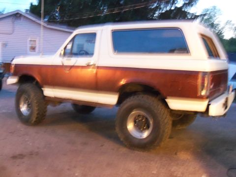 1989 Ford Bronco - This 1989 Ford Bronco features a two-tone paint scheme and lifted suspension, viewed from the rear three-quarter angle.