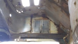 1978 Ford Bronco - The interior of this vehicle is severely rusted, with visible structural damage and a small, screened window.