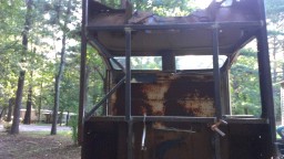 1978 Ford Bronco - This heavily rusted vehicle cab appears to be in a state of disrepair, with its metal frame exposed and windows shattered.