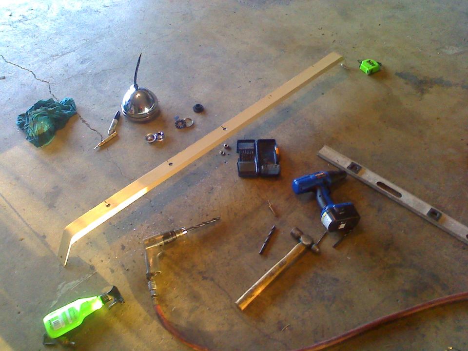 Hammer, drills, level, oil can, wood plank, and spray bottle on concrete