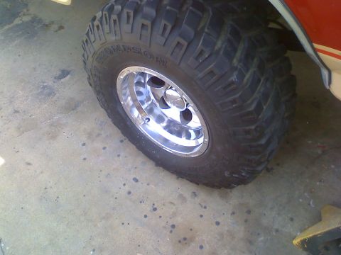 1990 Ford Bronco - A close-up view of a vehicle's large, aggressive off-road tire and shiny chrome rim.