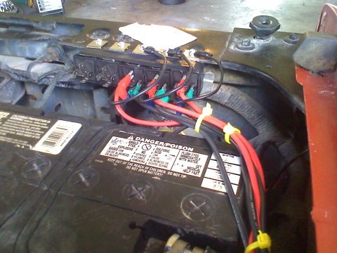1990 Ford Bronco - Close-up of a vehicle's engine bay, showing a battery and a fuse box with custom wiring.