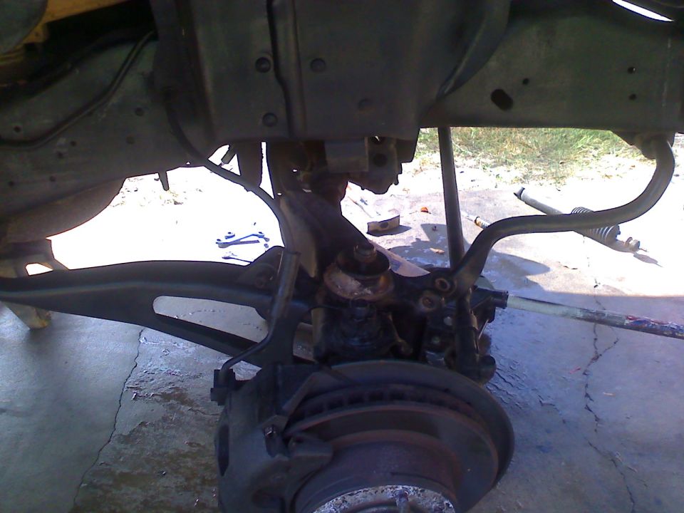 Close-up of vehicle suspension and brake assembly with Supermotors.net watermark