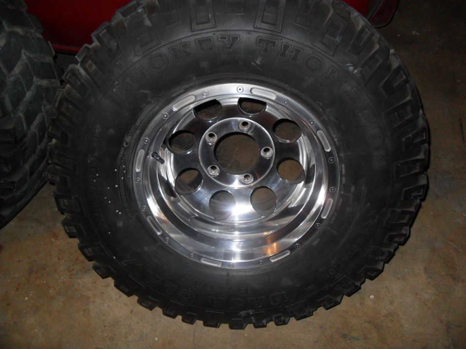 Tire with 'MICKEY THOMPSON' text and a chrome alloy wheel with six lug holes