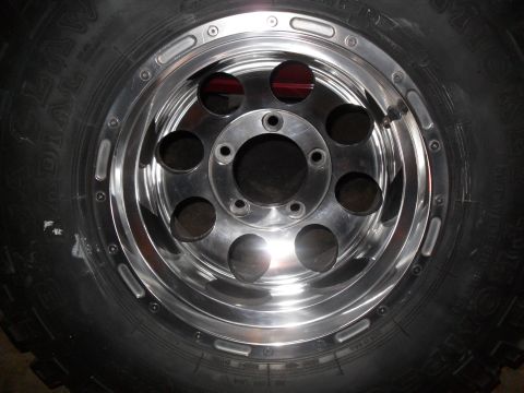 1990 Ford Bronco - Close-up of a chrome wheel and tire, with Supermotors.net branding in the corner.