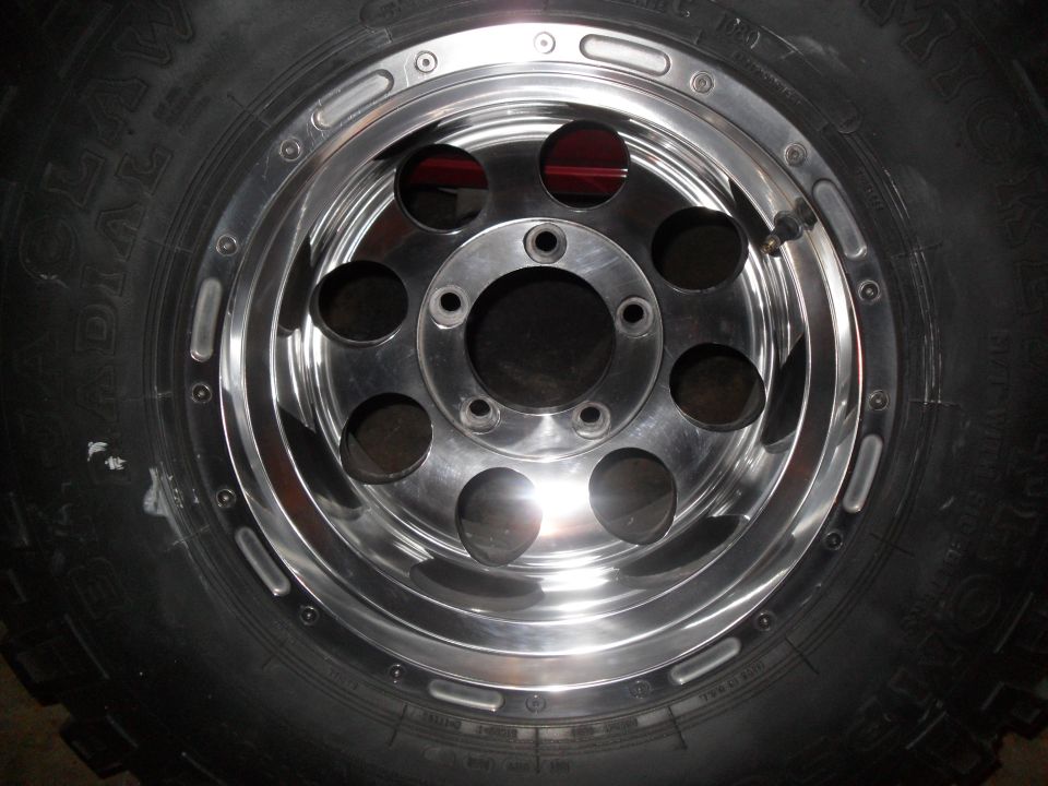 Chrome alloy wheel with lug nuts and a tire. Supermotors.net logo visible