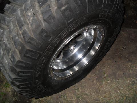 1990 Ford Bronco - A close-up shot focuses on a off-road tire mounted on a polished chrome wheel.