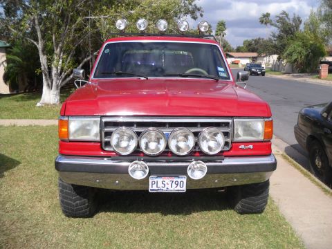 1990 Ford Bronco - Red 1990 Ford Bronco with multiple auxiliary lights mounted on the roof and bumper.