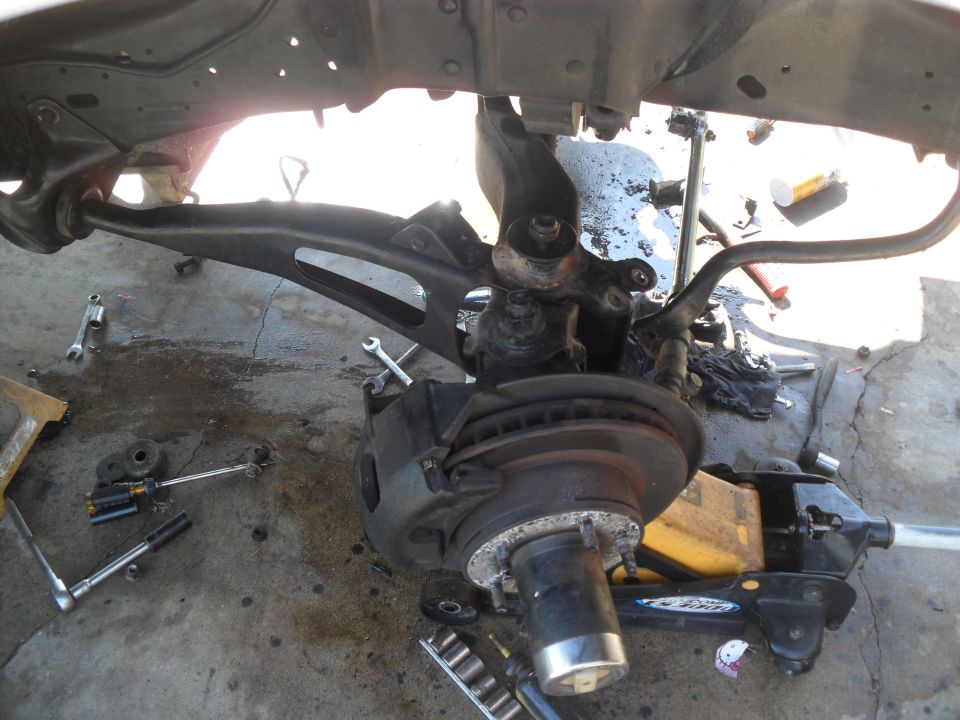 Vehicle front suspension assembly with brake rotor and caliper, on a concrete floor with tools