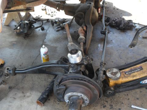 1990 Ford Bronco - Close-up view of disassembled vehicle suspension and steering components laid out on a concrete surface.