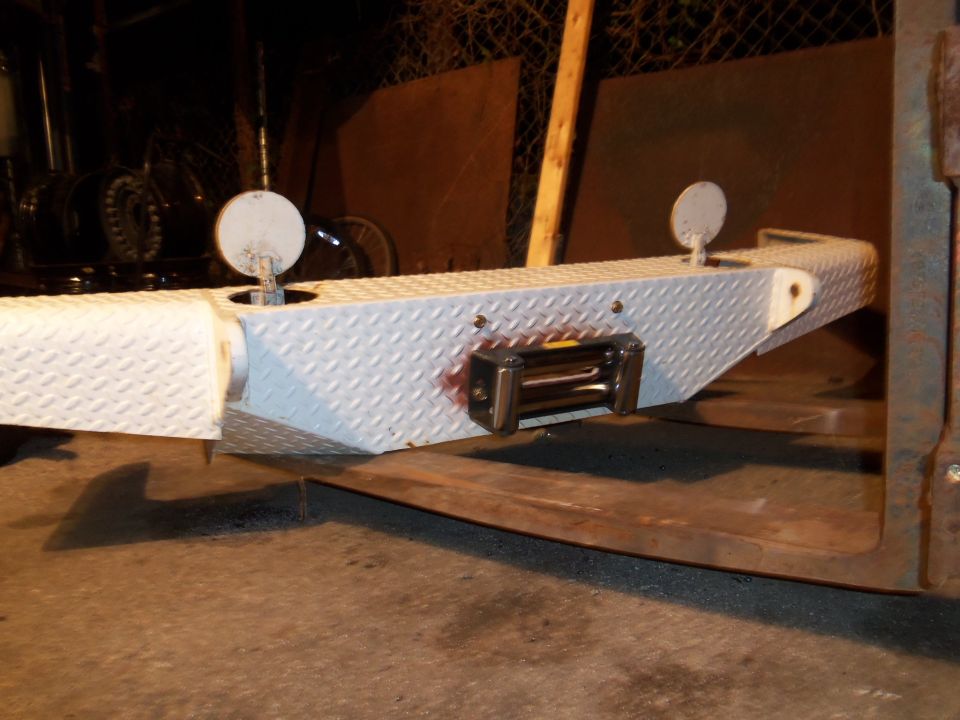 Diamond plate bumper with integrated winch, two circular covers, and red staining