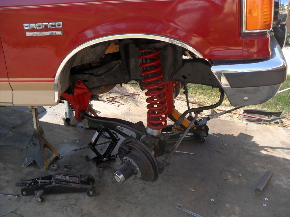 Red 1990 Ford Bronco front suspension disassembled